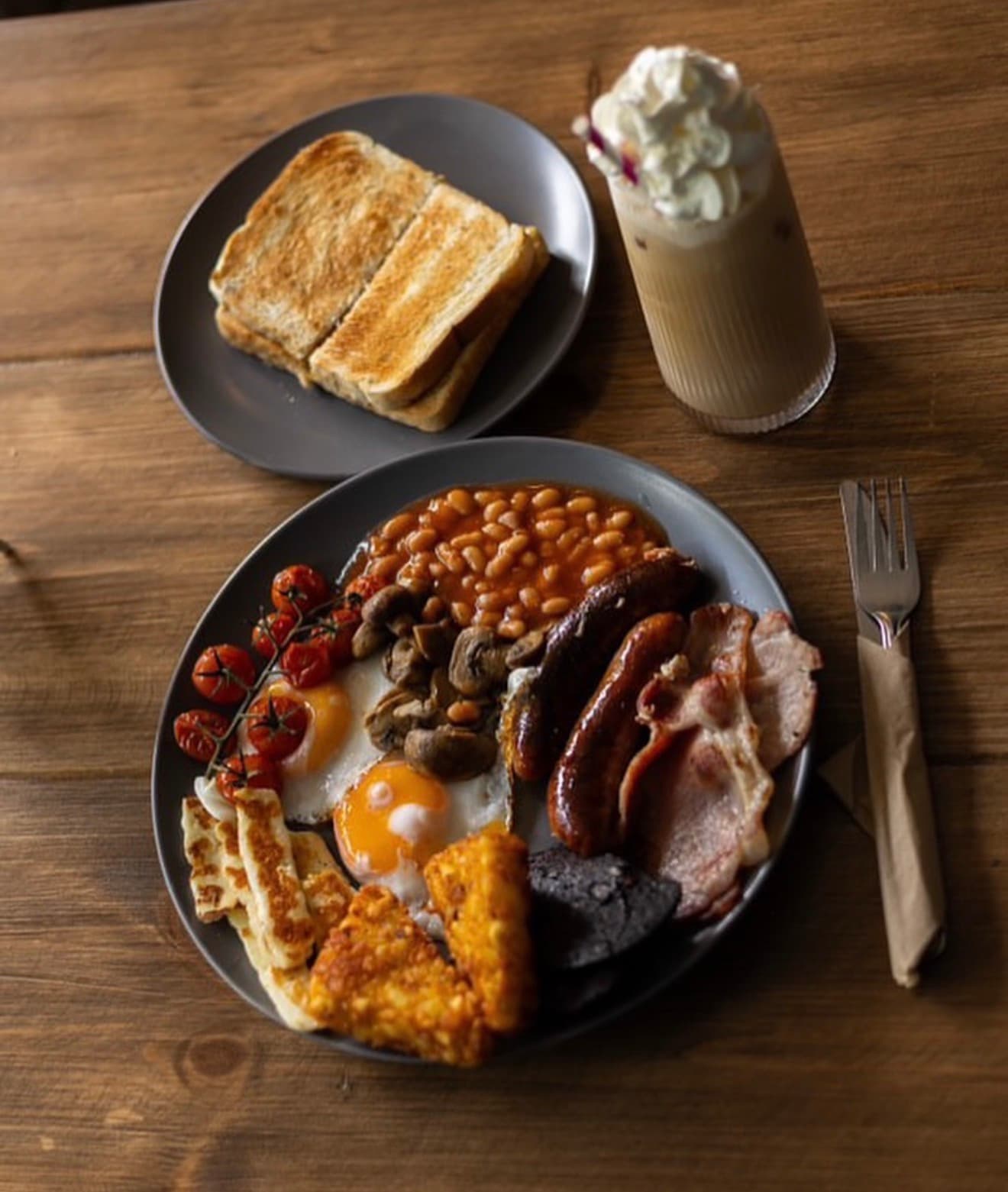 Full English breakfast, toast, and an iced coffee on the table