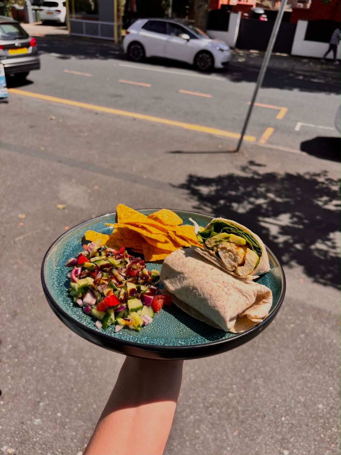 A wrap with salsa and nachos, held up on the street